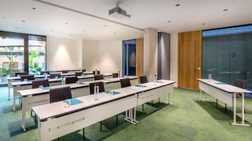 A conference room with long tables, chairs, and a projector.