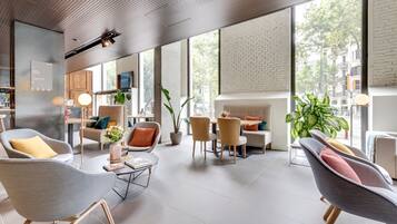 A modern hotel lobby with a spacious layout, large windows, and a mix of seating areas.