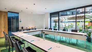 A conference room with a long table, chairs, and a large window with a view of the outside.