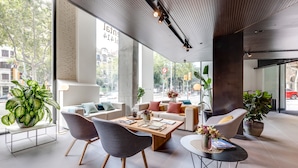 A modern, well-lit lobby with a large window, comfortable seating, and potted plants. - Occidental Diagonal 414 (Barcelona)