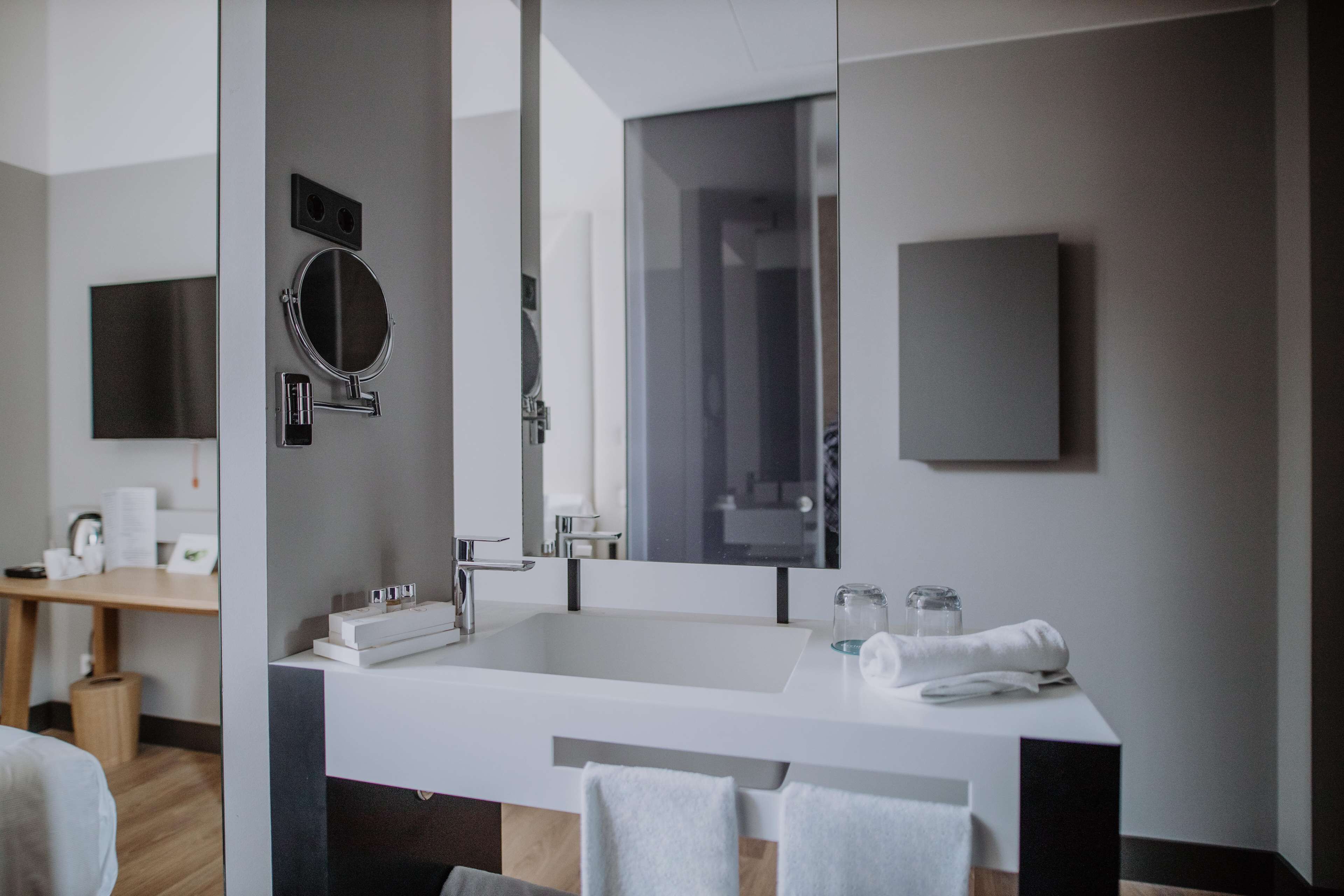 Une salle de bain moderne avec un grand miroir, un lavabo et un porte-serviettes.