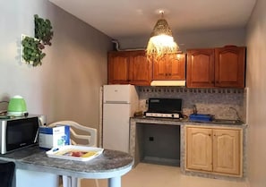 Enjoy cooking in this kitchen with a gas stove, microwave, and refrigerator, plus a dining area with a table and chairs.