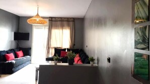 Ett modernt vardagsrum med en soffa, ett matbord och en hängande lampa.