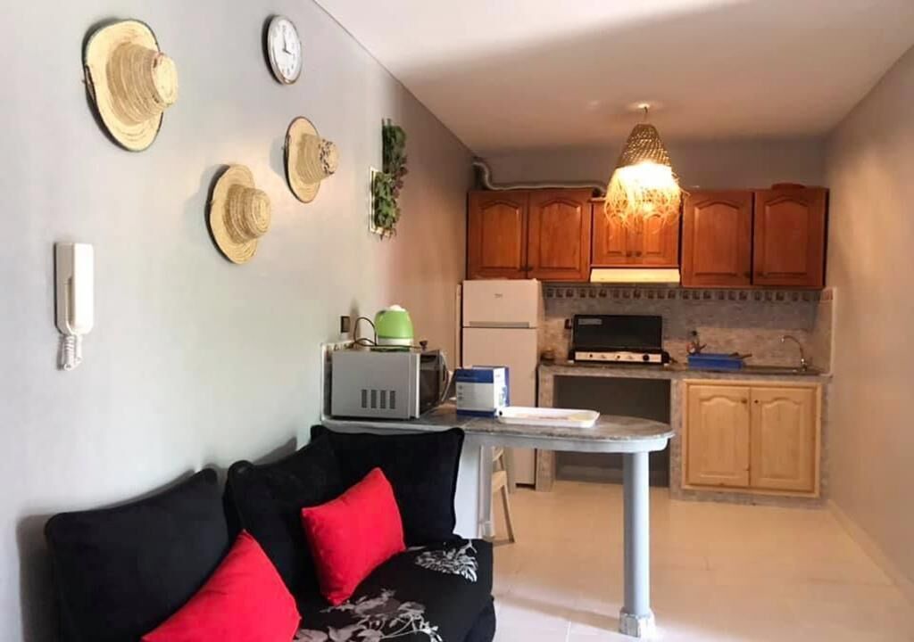 A compact living space with a sofa, a small table, and a kitchenette.