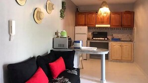 Ett kompakt bostadsutrymme med en soffa, ett litet bord och ett litet kök.