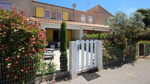 A two-story house with a covered patio, a white fence, and a garden with red-leaved plants. - Nice villa in residence CLOS DE SOCORRO with pool, 2 bedrooms, great View, PORTIRAGNES PLAGE (PORTIRAGNES)