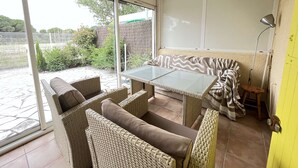 A covered patio with wicker furniture, a glass table, and a view of the outside. - Nice villa in residence CLOS DE SOCORRO with pool, 2 bedrooms, great View, PORTIRAGNES PLAGE (PORTIRAGNES)