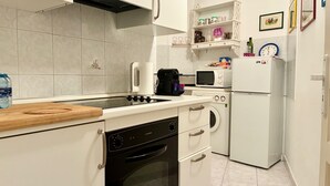 Une cuisine compacte équipée d’une cuisinière, d’un four, d’un four à micro-ondes et d’un petit réfrigérateur.