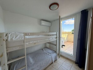 A bunk bed room with a window, a ceiling fan, and a door leading to an outdoor balcony.