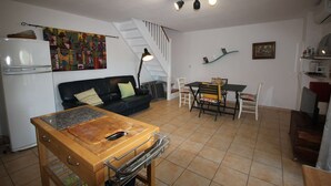 Un espace de vie compact comprenant une kitchenette, un coin repas et un escalier.