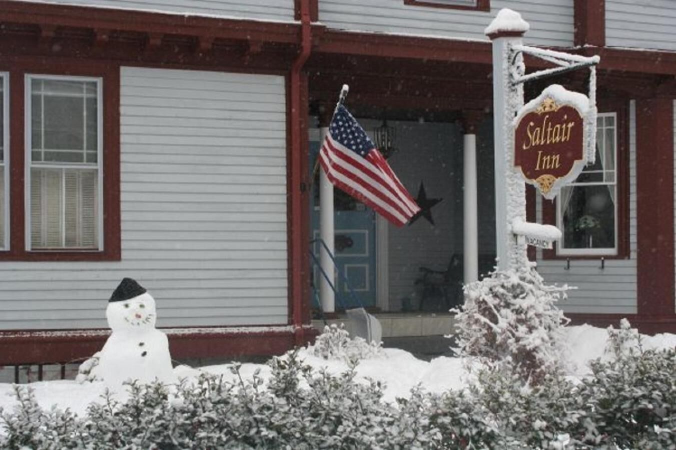 A hotel with a snowman decoration, an American flag, and a sign reading "Saltair Inn".
