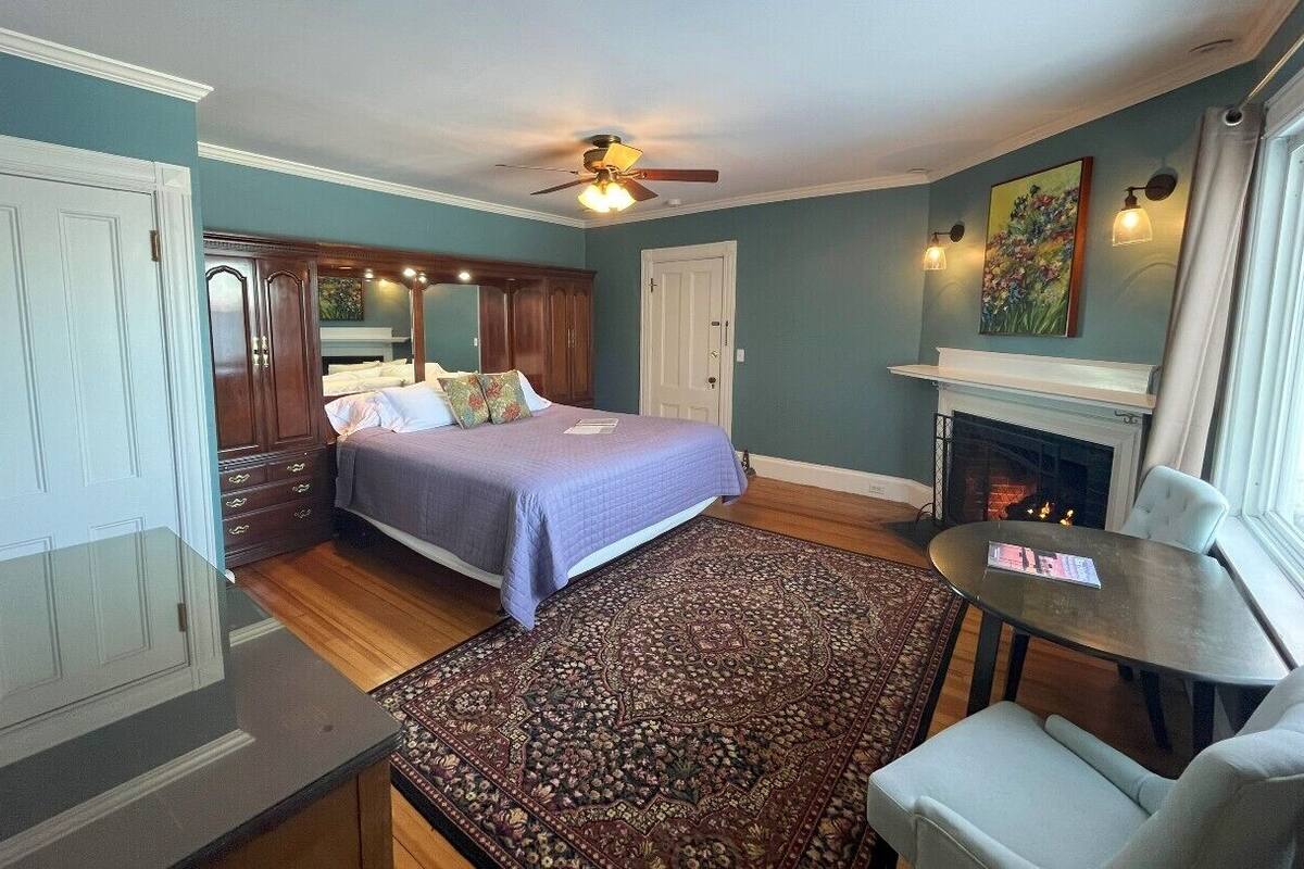 A bedroom with a bed, a fireplace, a table, and a chair.