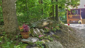 A natural outdoor area with a wooden deck, large rocks, and potted plants. - Harrah's/Cherokee/Lakes/rafting/ fishing/hiking/waterfall/Elk/rejuvenating peace (Maggie Valley)