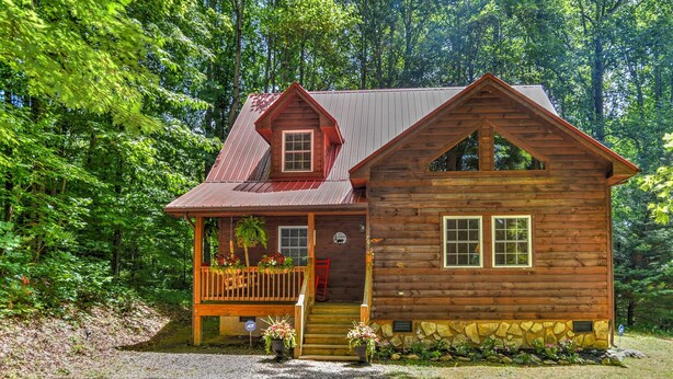 A wooden cabin with a porch, a stone foundation, and a metal roof, surrounded by dense forest. - Harrah's/Cherokee/Lakes/rafting/ fishing/hiking/waterfall/Elk/rejuvenating peace (Maggie Valley)