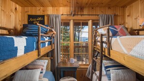 Une cabine avec des lits superposés, une petite table et une fenêtre avec des rideaux.