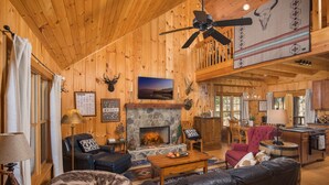 L’intérieur d’un chalet confortable, avec une cheminée, des meubles en cuir et un ventilateur de plafond.