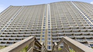 A high-rise building with a grid of balconies, a central stairwell, and a wooden viewing platform.