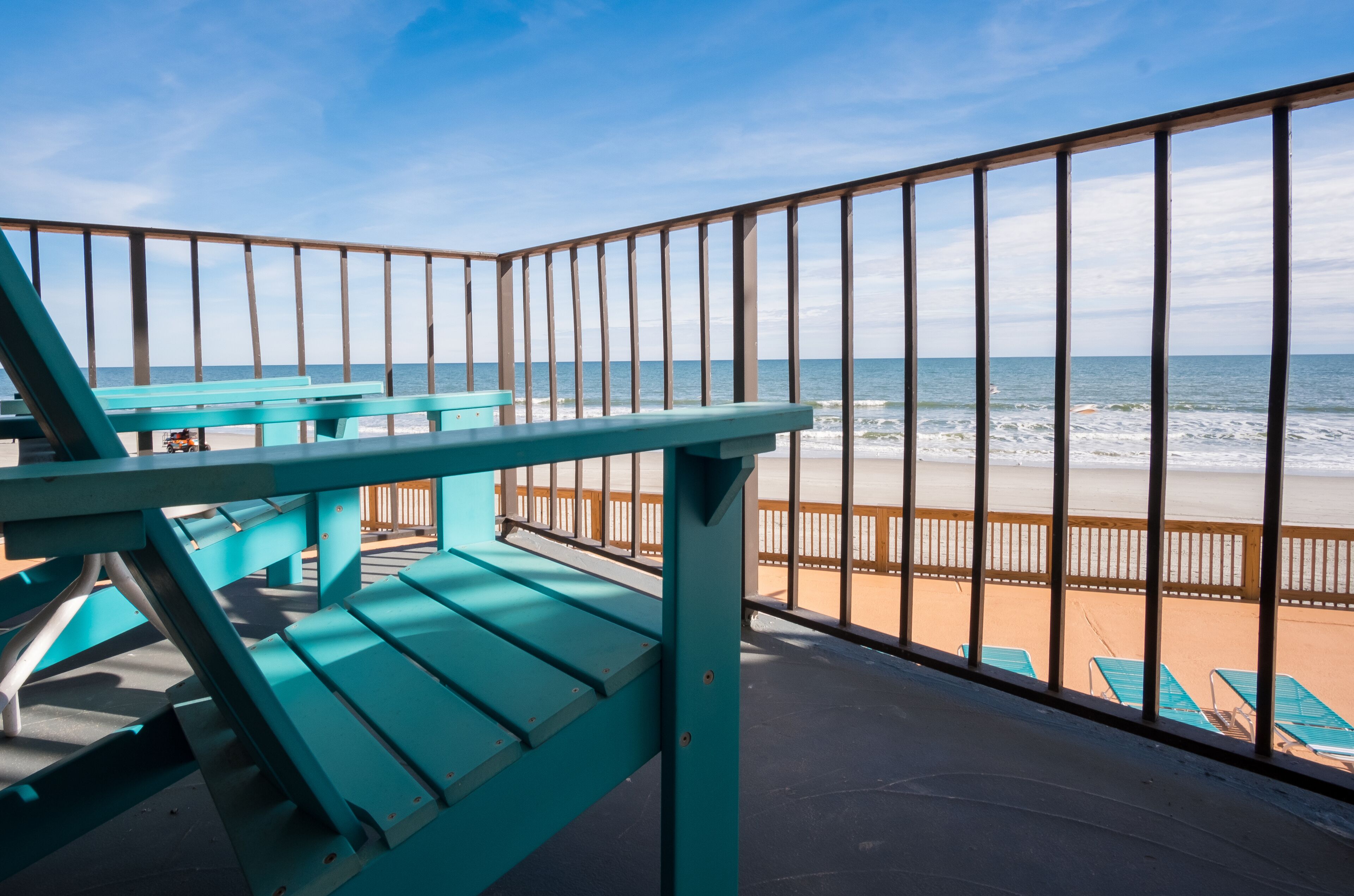 A balcony with a view of the beach and ocean.