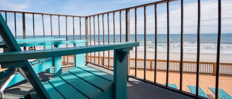 A balcony with a view of the beach and ocean.