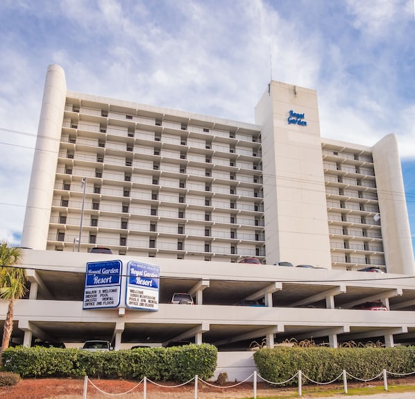 A multi-story hotel with balconies, a parking garage, and signs indicating amenities like indoor pools and spas. - Scenic Ocean front first floor pool view spacius condo for up to 4 adults. (Garden City)