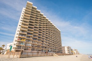 A modern high-rise hotel with multiple balconies, located on a beach with a clear sky. - Scenic Ocean front first floor pool view spacius condo for up to 4 adults. (Garden City)