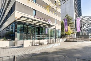 Un hôtel Premier Inn doté d’une façade moderne en verre, d’un espace extérieur aménagé et offrant une vue dégagée sur le quartier urbain environnant.