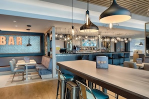 Een moderne bar met een bakstenen muur, barstoelen en hanglampen.