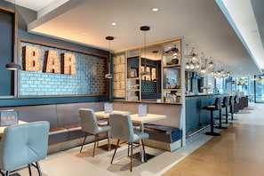 Een bar met verlichte ‘BAR’ letters, zitplaatsen en een verzameling speelgoed.