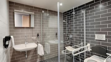 Ein modernes Badezimmer mit einer gläsernen Duschkabine, einem Waschbecken mit Handtuchhalter und einer Toilette.
