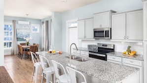 A modern kitchen with white cabinets, a granite countertop, and stainless steel appliances.