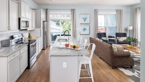 A modern kitchen with white cabinets, a granite countertop, and a central island with breakfast items.