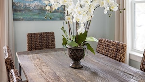 A rustic wooden table with a vase of white orchids.