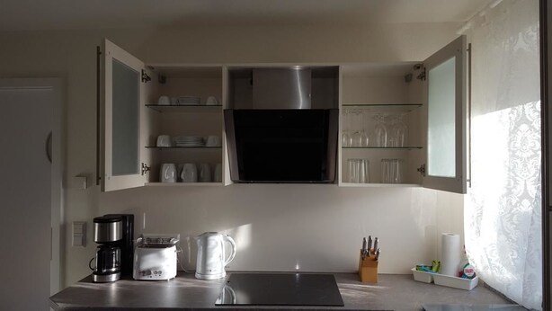 Een keuken met open kastjes, een koffiezetapparaat, een broodrooster, een waterkoker en een messenblok.