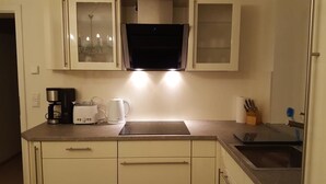 Een keuken met een ingebouwde magnetron, koffiezetapparaat en waterkoker.