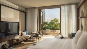 A modern hotel room with a large bed, a TV, a seating area with a table, and a balcony with a view of the city. - Four Seasons Hotel Bangkok at Chao Phraya River (Bangkok)