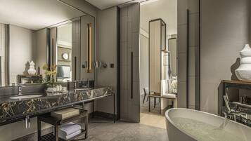 Une salle de bain moderne avec un grand miroir, deux lavabos, un meuble-lavabo et une baignoire sur pieds.