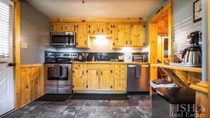 Una cocina con armarios de madera, electrodomésticos de acero inoxidable y salpicadero de azulejos.