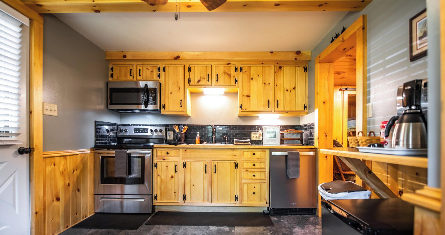 Una cocina con armarios de madera, electrodomésticos de acero inoxidable y salpicadero de azulejos.
