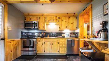 Una cocina con armarios de madera, electrodomésticos de acero inoxidable y salpicadero de azulejos.