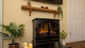 A cozy room with a black wood-burning stove, a potted plant, and candles on a marble countertop. - Belmont House Beer - Adults Only (Seaton)