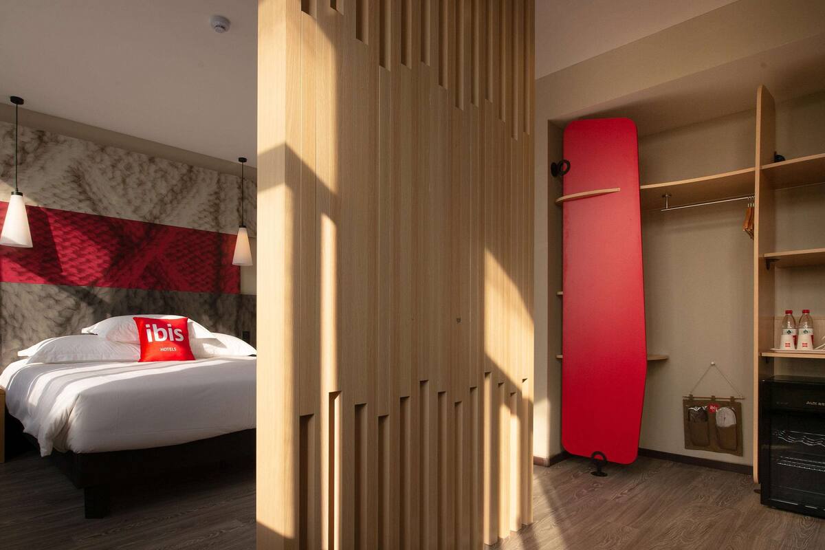 Ein Hotelzimmer mit einem Bett, einem Kleiderschrank und einer roten Wand.