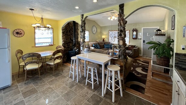 A cozy living room with a fireplace, a dining area with chairs and a table, and a kitchen area with a refrigerator and a sink. - Middle of town lodge style cottage (Silver City)