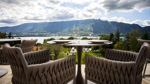 Una mesa con dos copas de vino y un plato, frente a una vista panorámica de la montaña.