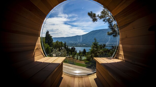 Una estructura de madera circular con vistas panorámicas a un lago, montañas y árboles.