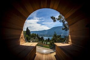 Een ronde houten constructie met een panoramisch uitzicht op een meer, bergen en bomen.