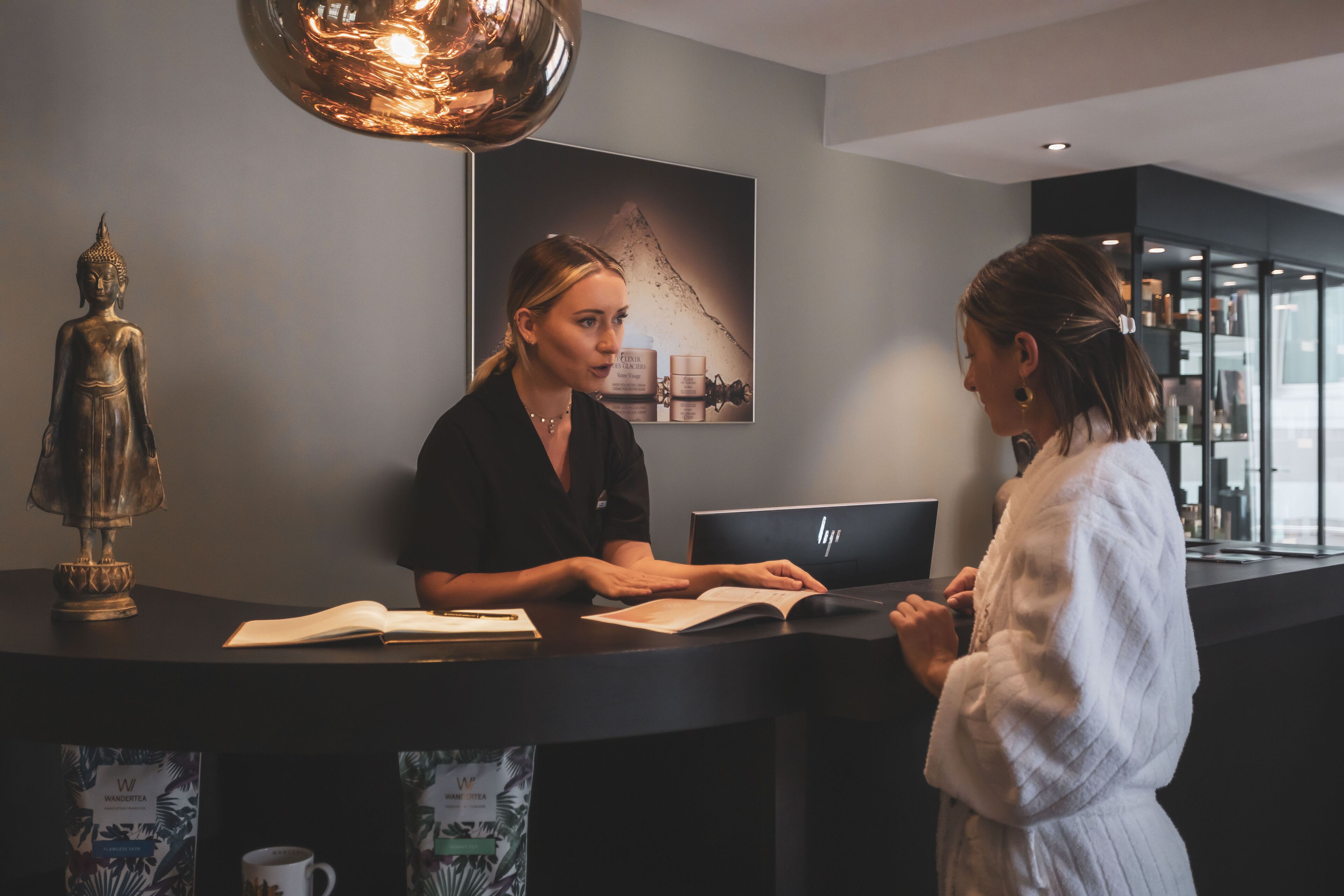 A reception desk with a laptop, a Buddha statue, and a framed picture on the wall.