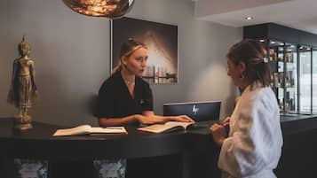 A reception desk with a laptop, a Buddha statue, and a framed picture on the wall.