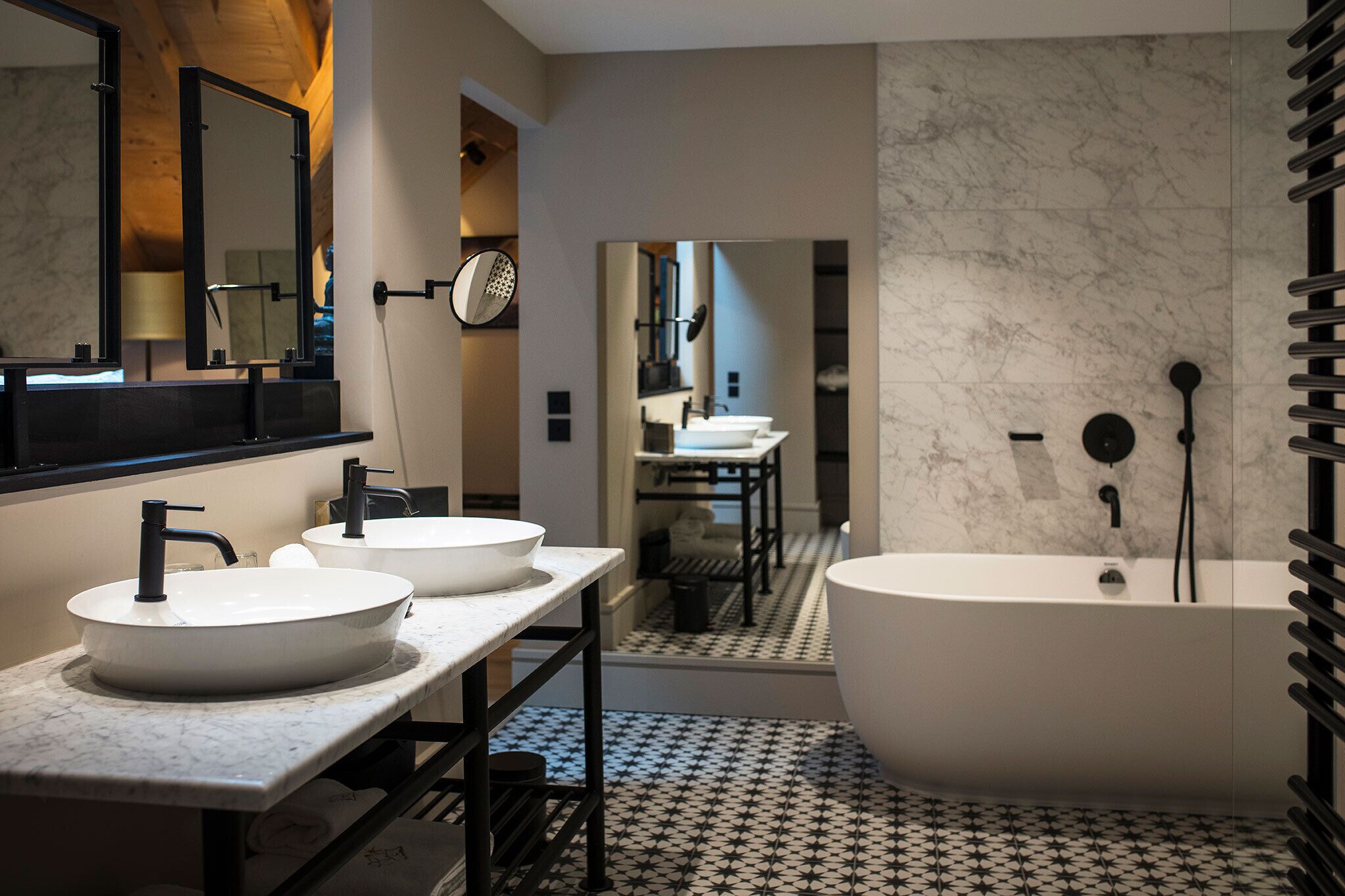 A modern bathroom with two sinks, a bathtub, and a mirror.