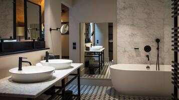 A modern bathroom with two sinks, a bathtub, and a mirror.