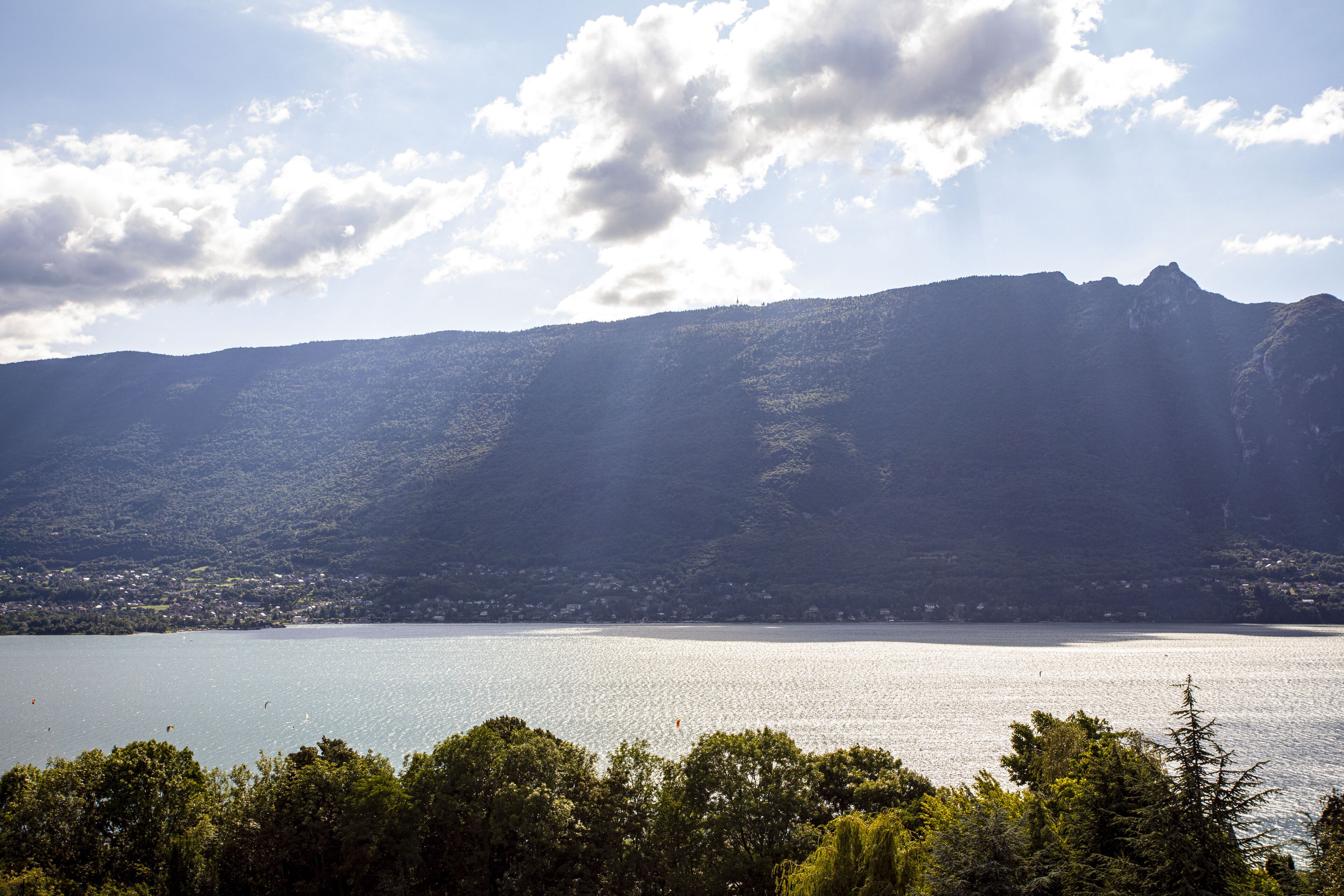 Un lago con montagne sullo sfondo e alberi in primo piano.